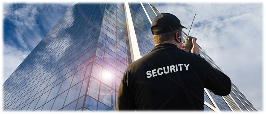 איש אבטחה עומד מתחת לגורד שחקים ומחזיק מכשיר קשר